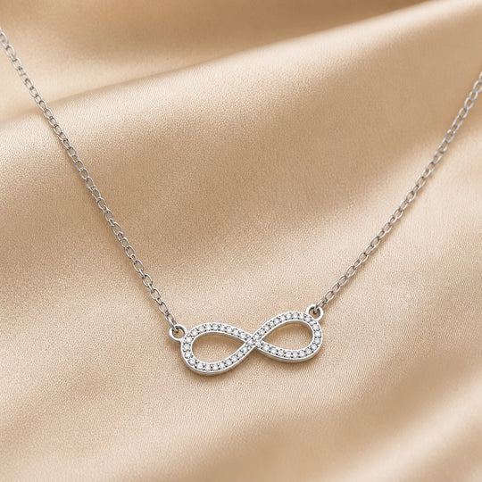 Collier en or blanc avec pendentif en forme d'infini et zirconia.